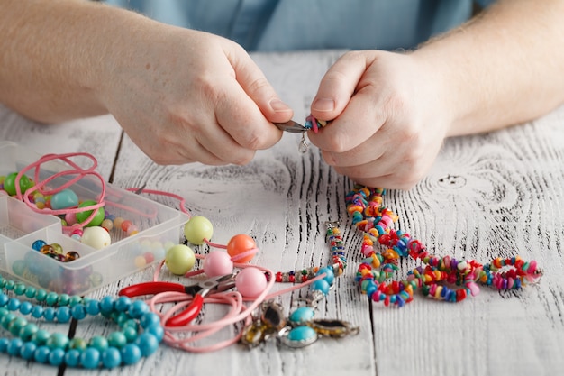 Male hands making a necklace with wooden beads