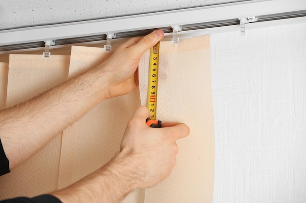 Male hands measuring vertical blinds