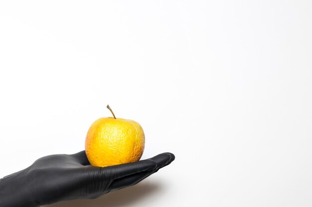 Male hands in medical gloves with wrinkled apples and a syringe in hands on a white