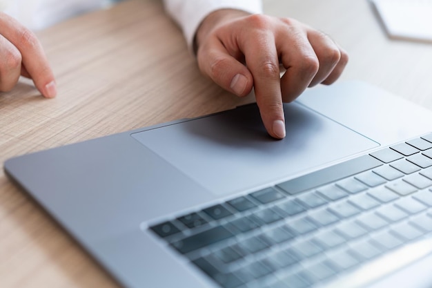Мужчина вручает офис-менеджеру нажатие сенсорной панели на ноутбуке крупным планом мужские руки с серым ноутбуком Мужчина-офис-менеджер, работающий с компьютером без лица Концепция работы