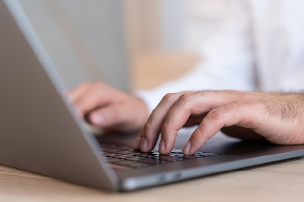 Male hands office manager typing on laptop closeup of man hands on black keyboard Man office manager working with computer no face Concept of work