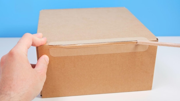 Foto mani maschili che aprono una scatola di cartone con strappo del nastro scatola di cartone marrone disimballaggio consegna pacchi