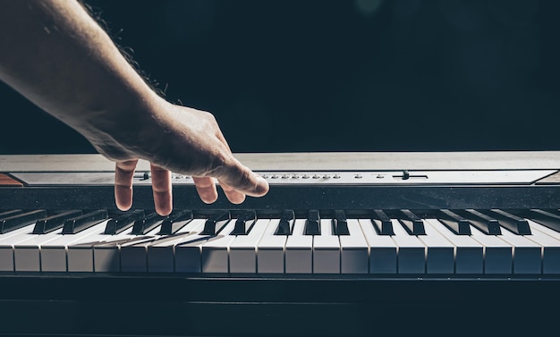 Male hands play the piano keys in the dark