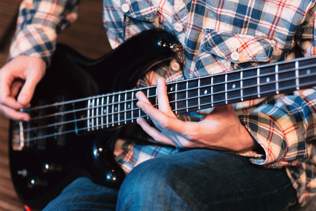 Male hands playing on bass guitar