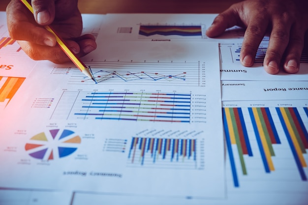 Photo male hands pointing at turnover graph while discussing it on wooden desk in office