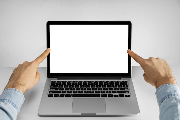 빈 흰색 화면이 노트북 컴퓨터에서 검지 손가락으로 가리키는 남성 손