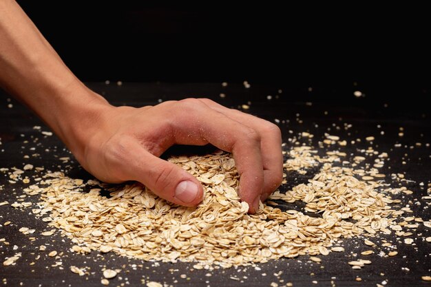 Male hands pouring muesli on a black background