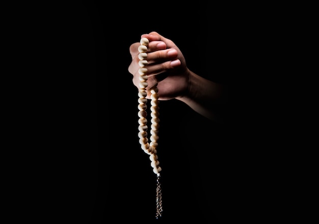 Male hands praying using prayer beads