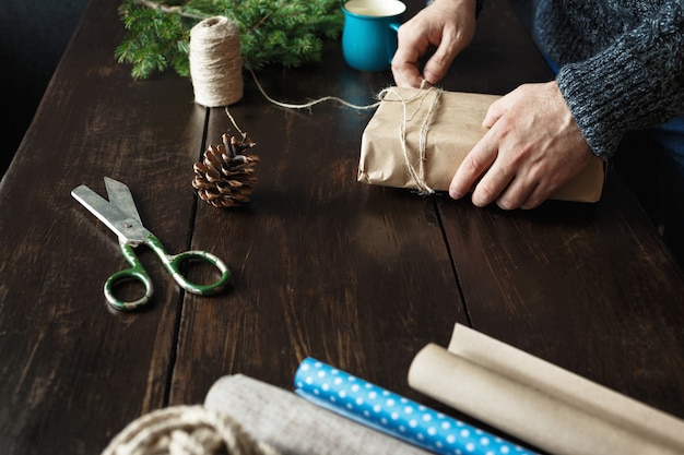 Male hands preparing Christmas present wooden table Rustic Christmas 