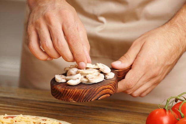 Foto mani maschili che preparano la pizza a un primo piano sul tavolo di legno