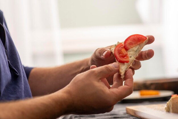 Foto mani maschili che preparano un panino con formaggio e pomodoro