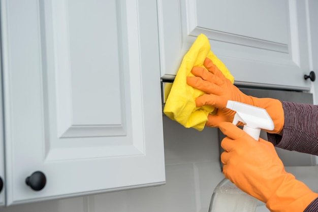 Male hands in protective gloves cleaning the kitchen hood with rag and spray bottle . housekeeper