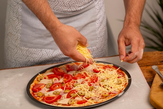 male hands putting food on pizza