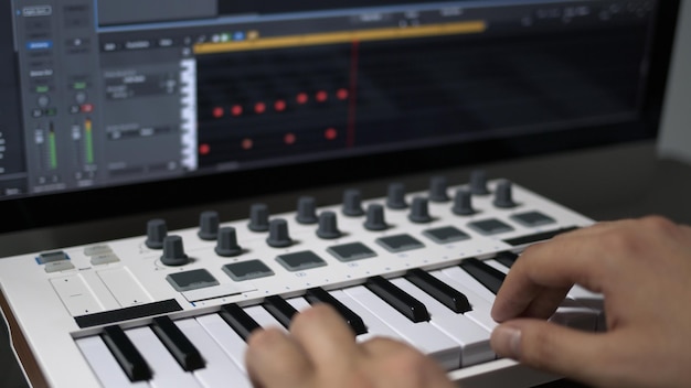 Male hands recording midi keyboard in sequencer in computer in\
home studio