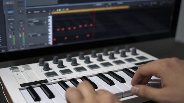 Foto mani maschili che registrano la tastiera midi nel sequencer nel computer in home studio