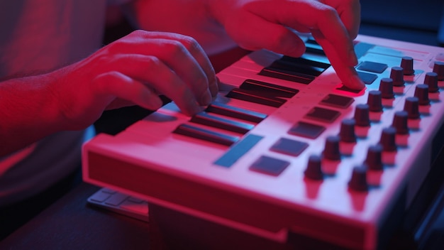 Male hands recording music using midi keyboard in home studio\
neon lights