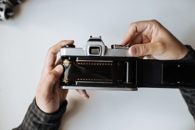 Male hands reloading film retro camera on a white table