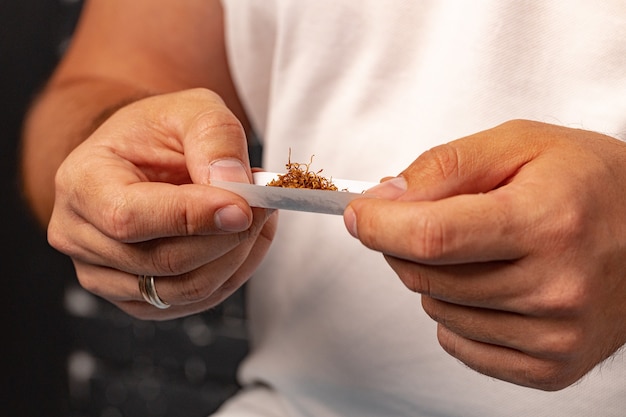 Il maschio passa il tabacco da arrotolare in carta da sigarette