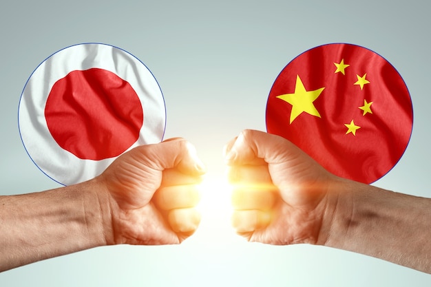 Male hands show their fists against the background of the flags of Japan and China.