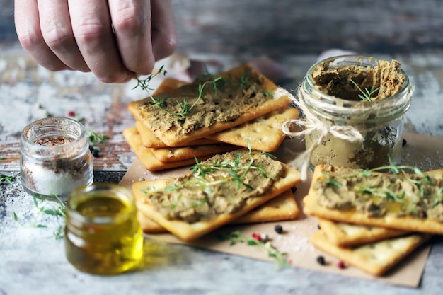 Male hands smear homemade paste on cracker. Fresh homemade pate.