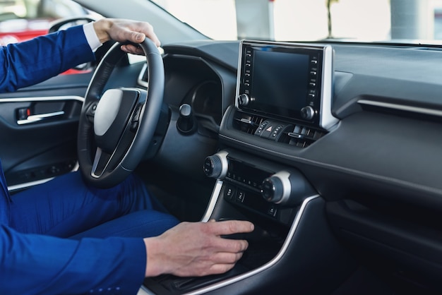 Male hands on steering wheel, car interior