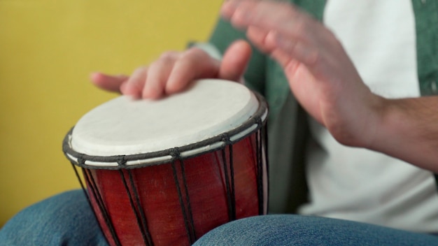 Male hands tapping djembe, bongo in rhythm.