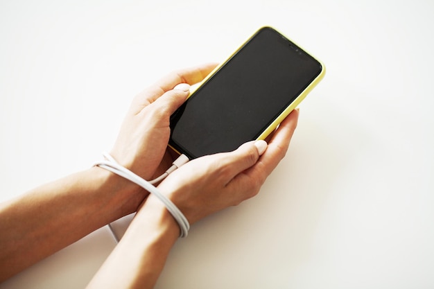 Male hands tied with chain and hold smartphone