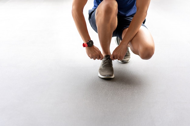 男性の手が練習の前にランニングシューズの靴ひもを結ぶこと。