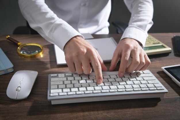 コンピューターのキーボードで入力する男性の手。