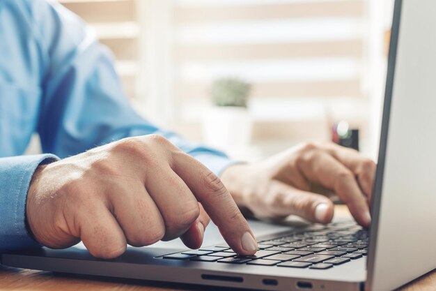 Male hands typing on a laptop keyboard, close-up view