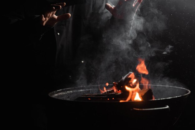 Male hands of an unrecognizable person warm themselves near the fire of a barrel in the dark Homeless emigrant beggar concept