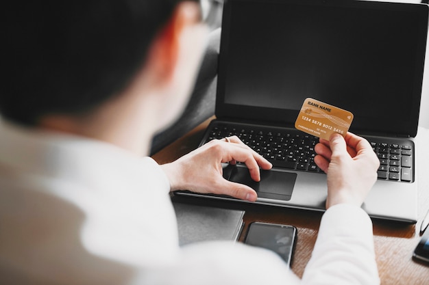 Male hands using a credit card and a laptop for online operation or internet banking.