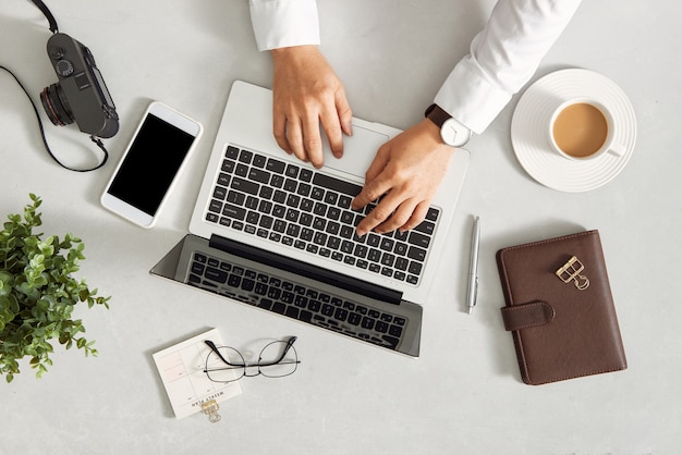 Male hands using laptop with black screen at white desk. Office supplies