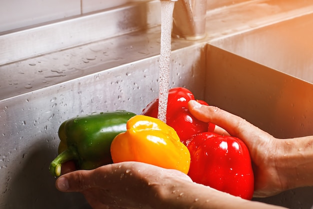 Male hands wash yellow paprika. bell pepper under water flow. food from farmer's market. always wash vegetables before slicing.