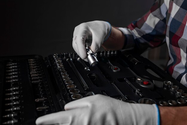 Male hands in white gloves over open toolkit with metal tools for car and home repair, close up.