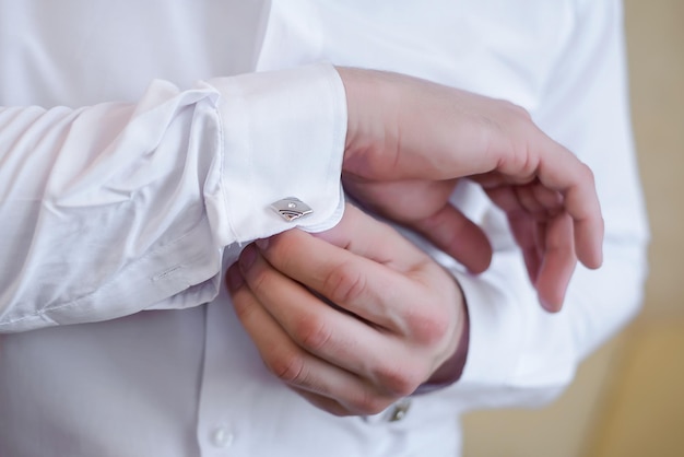 Male hands in a white shirt beautiful button cuff links on the sleeves close up
