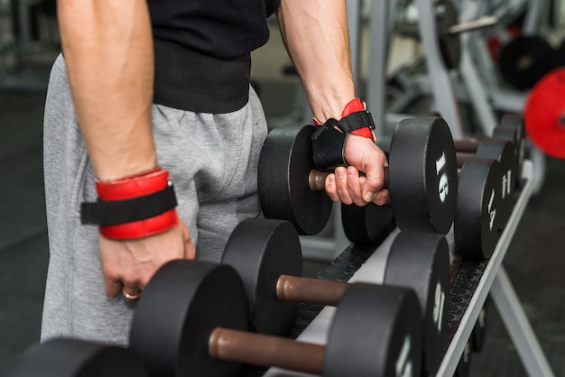 Mani maschili con manubri in palestra da vicino