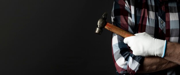 Male hands with hammer tool with black background and copy space for text. Banner.