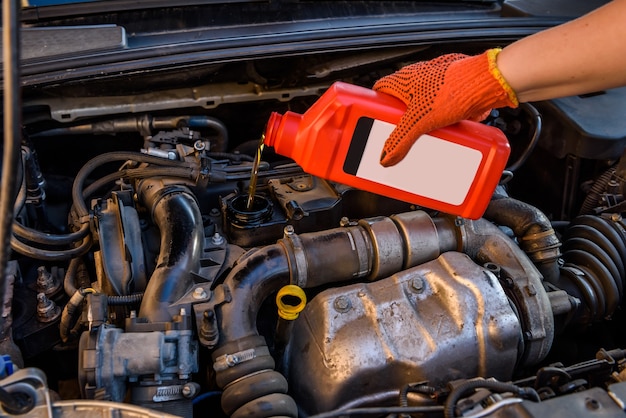 Male hands with oil bottle above car engine