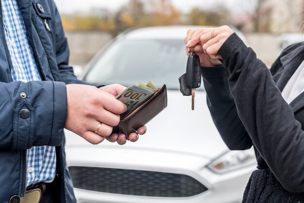 Mani maschii con portafoglio e mani femminili con chiavi dall'auto