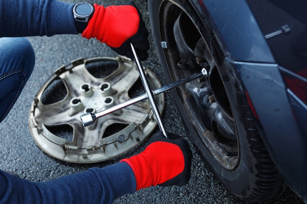 Male hands with wrench. Man changing flat tire on his car after road accident