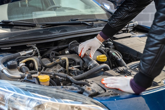 Male hands with a wrench repair to engine in the open hood of\
the car