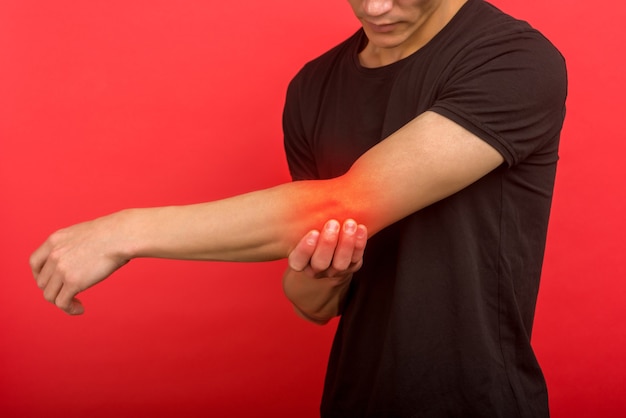 Male having elbow pain in injured arm on background - image