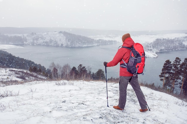 Male hiker hiking with backpack and nordic walking poles in winter nature active healthy lifestyle adventure journey vacations