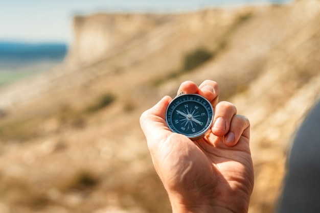 A male hiker is looking for a direction with a magnetic compass in the mountains in the fall.