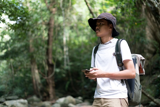 Photo a male hiker using the phone in forest