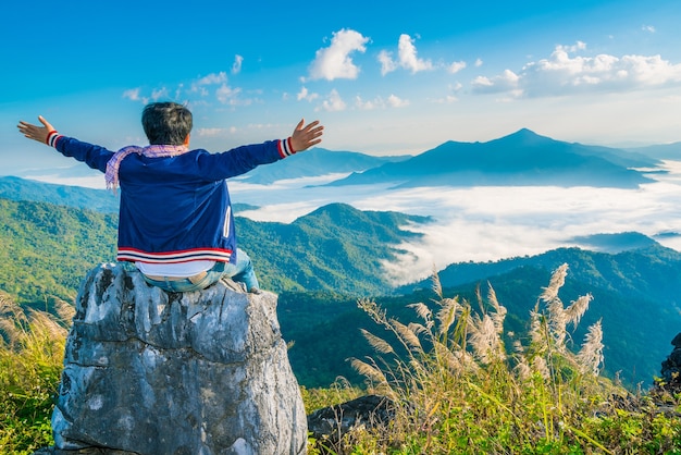 Photo male hipster traveler sit on the stone with beautiful mountain