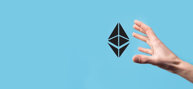 Male holding a Ethereum icon on blue surface.
