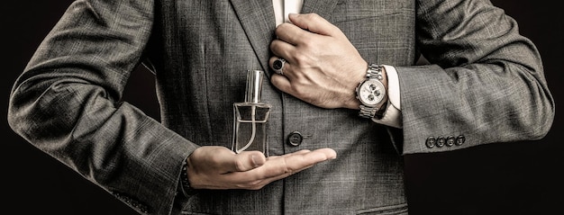 Male holding up bottle perfume Hand in with wrist watch in a business suit Perfume or cologne bottle and perfumery cosmetics scent cologne bottle male holding cologne