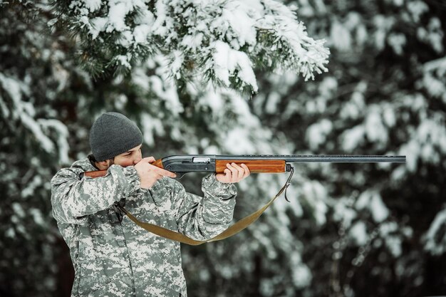 Male hunter in camouflage looking for his target or prey Winter scene